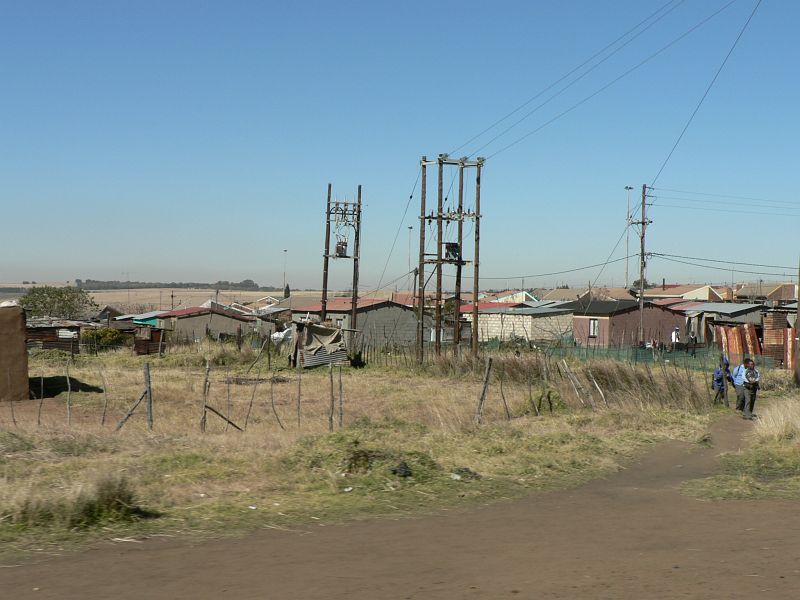 JAR 423.JPG - Velmi zřídka jsme projížděli nějakým městem, a i to spíše připomínalo slum. U jednoho z nich jsme viděli i nejzbytečnější povolání vůbec. Muž, který varoval před dírou v silnici. Místo aby ji opravil, nebo aby tam dali dopravní značku. Tak tam stál muž, který mával a ukazoval na výmol v silnici.</